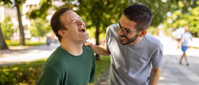 Caregiver and disabled young man laughing at the park