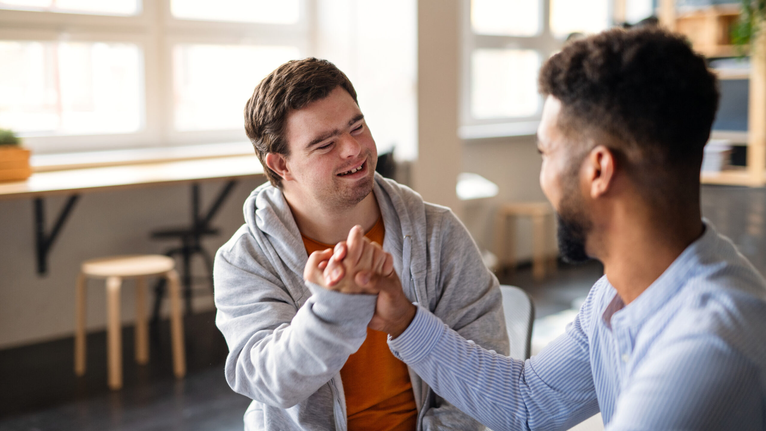 young man with developmental disability holding hands with his caregiver