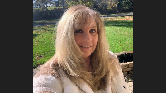 woman with long blonde hair smiling and taking a selfie