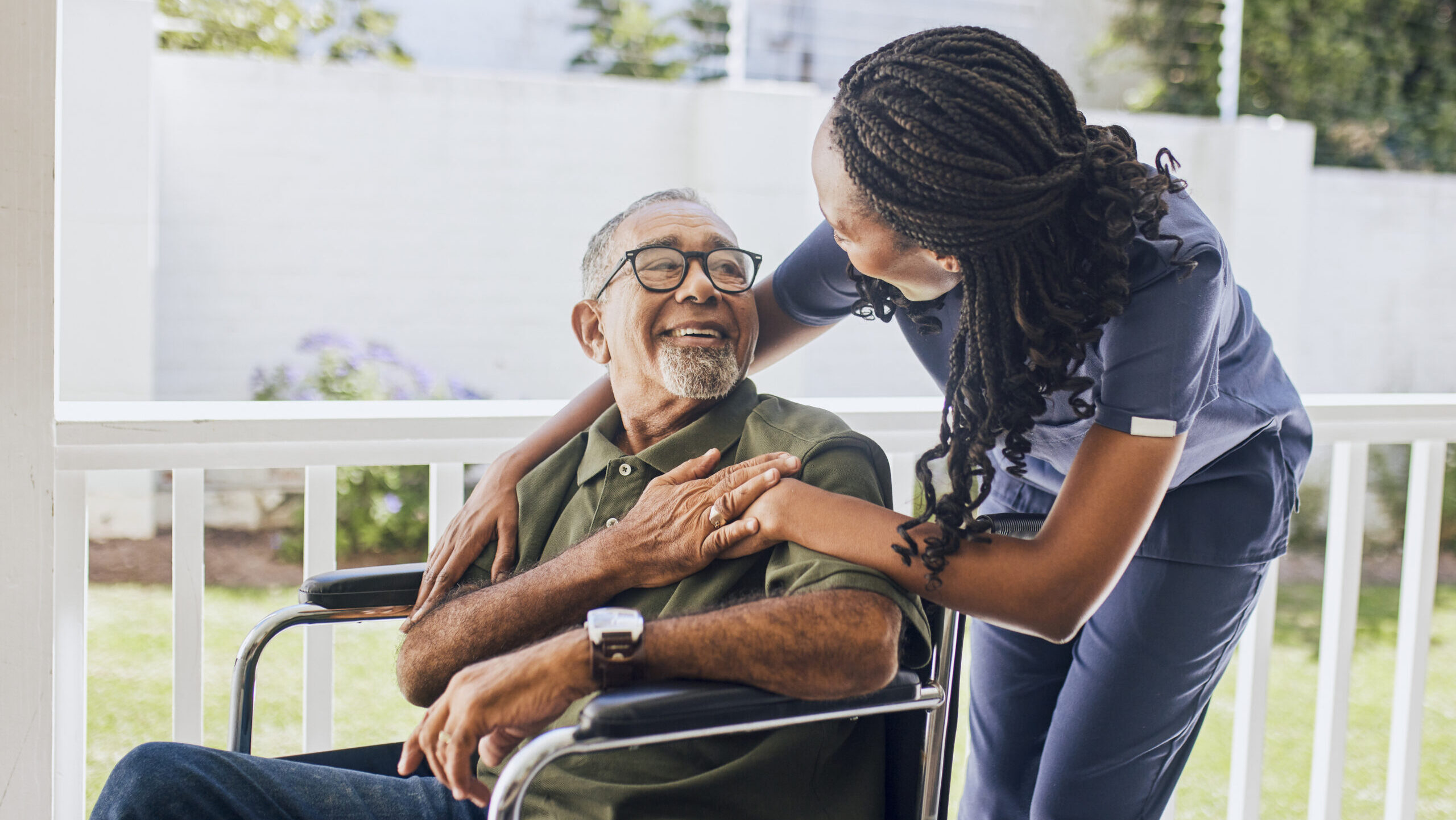 Young female nurse hugging an elderly man in a wheelchair