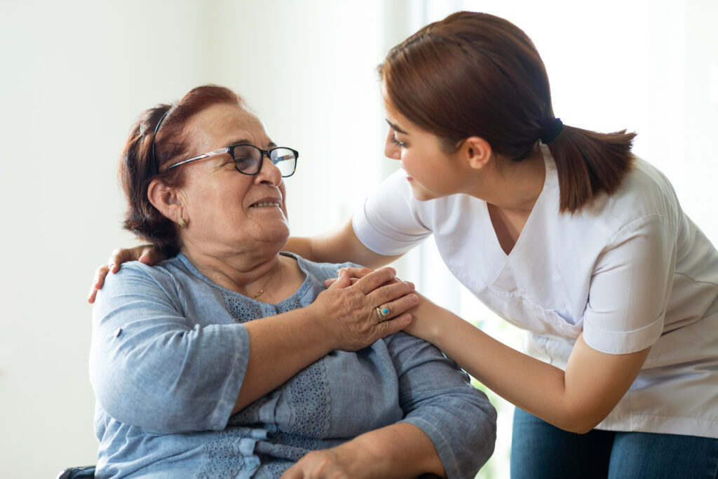 Caring nurse talks with female patient while holding hands
