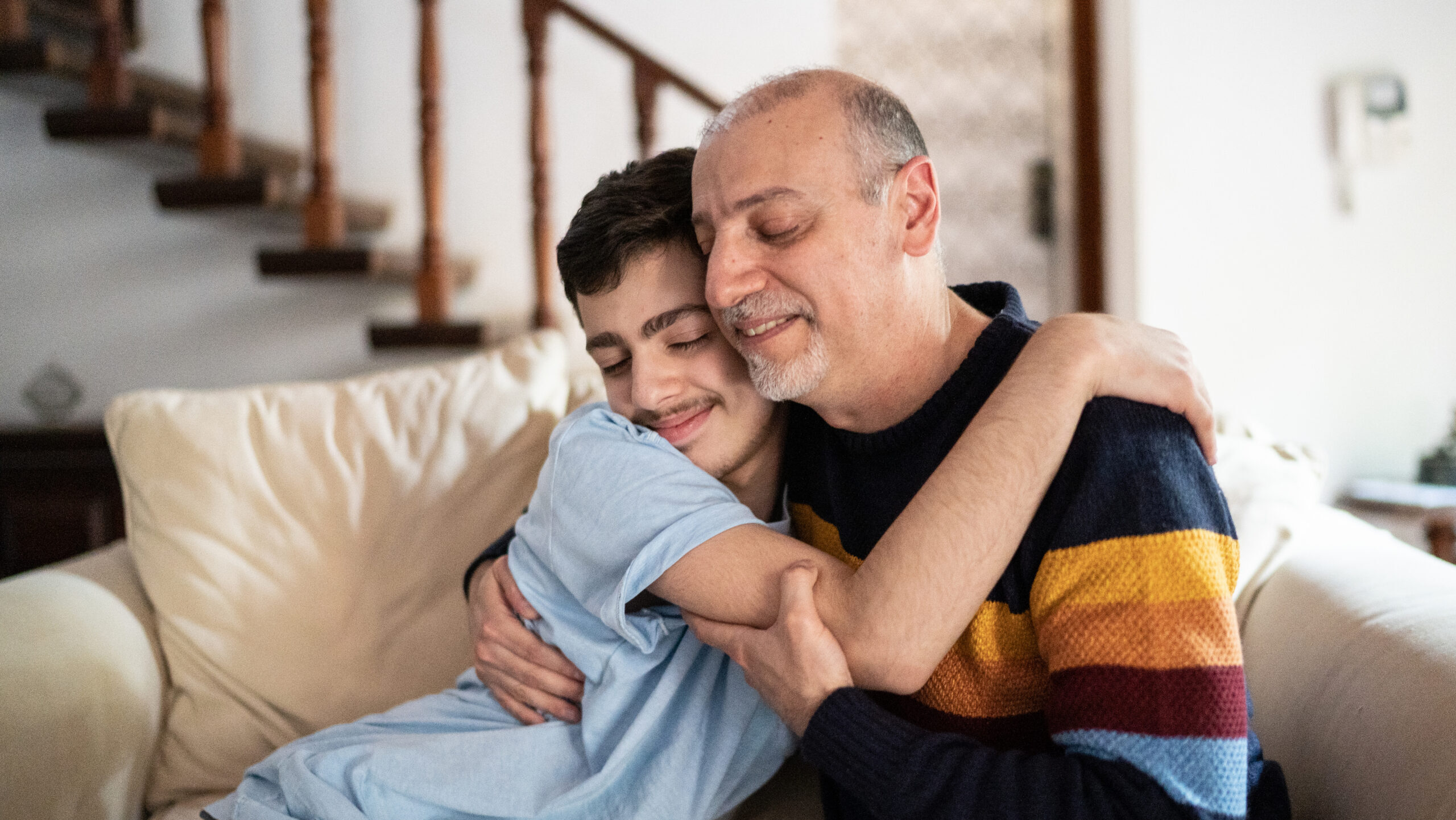 male participant and male caregiver hugging, one is younger and one is older