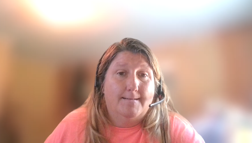 female PPL employee smiling, with blonde hair, a pink shirt, and a headset on her head
