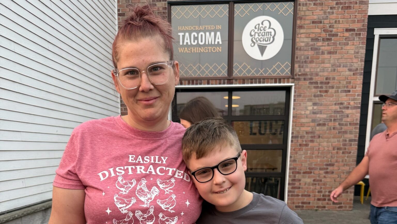 female PPL employee in a pink shirt posing with her middle school-aged son. they are both wearing glasses and smiling