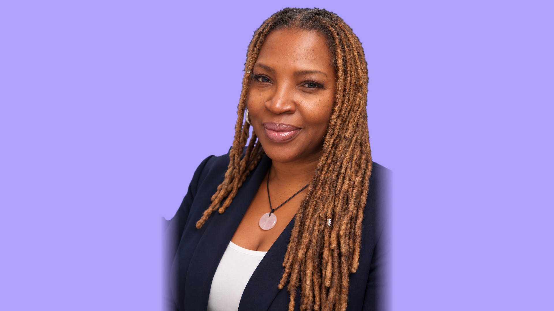 Smiling woman with long hair in a navy blazer on a lavender background